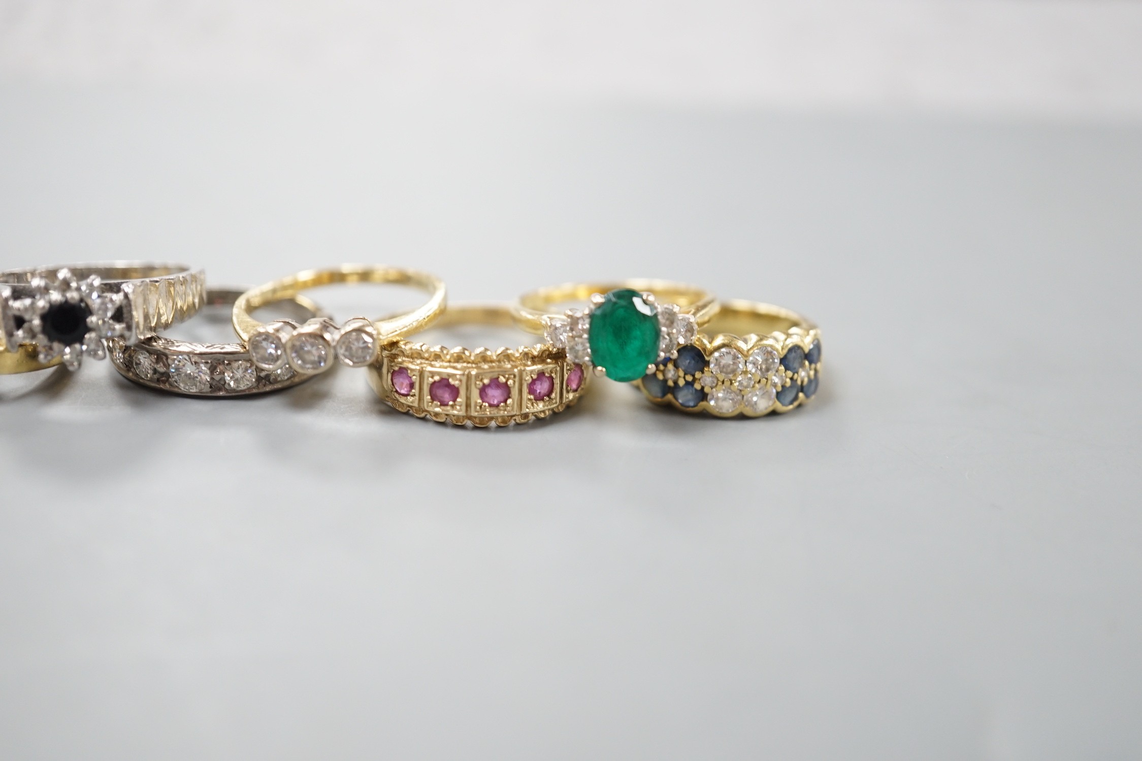 Seven assorted mainly modern 18ct gold or 750 yellow metal and gem set dress rings including emerald and diamond and diamond half eternity, gross weight 26 grams and one 9ct gold and gem set ring, gross 2.9 grams.